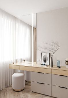 an empty room with white curtains and wooden flooring is seen in this image, there are two round stools on the far side of the table