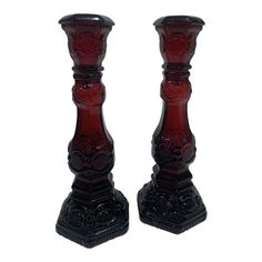 a pair of red glass candlesticks sitting next to each other on a white background