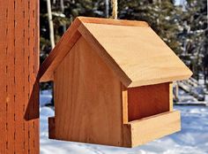 a wooden birdhouse hanging from a tree in the snow