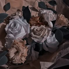 a bouquet of white and pink roses on a brown background with leaves in the middle