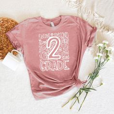 a pink t - shirt with the number two on it and some flowers next to it