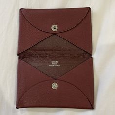 a red and brown card case sitting on top of a white sheet