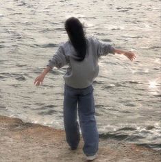 a woman throwing a frisbee on the beach near the water's edge