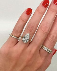 a woman's hand with three different rings on her fingers and one has a pear shaped diamond