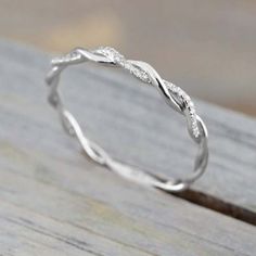 a white gold wedding band with twisted leaves on the side, sitting on a wooden surface