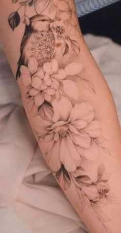 a woman's arm with flowers on it and a bird sitting on the branch