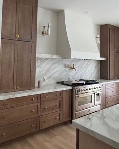 a kitchen with marble counter tops and wooden cabinets, along with stainless steel oven hoods