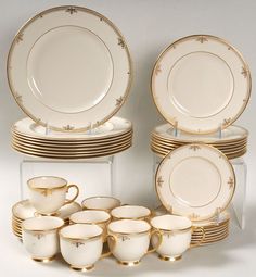 a table topped with lots of white and gold china cups and saucers on top of each other