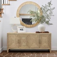 a living room with a large mirror on the wall next to a dresser and stairs