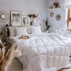 a white bed sitting in a bedroom next to a window with pictures on the wall