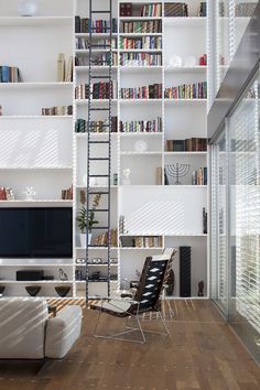 a living room filled with white furniture and bookshelves next to a flat screen tv