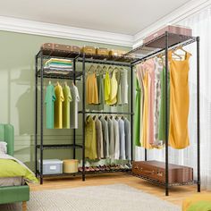 an open closet with clothes hanging on the rack, and a bed in the foreground