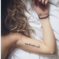 a woman laying in bed with her arm tattoo