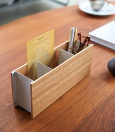 a wooden desk with a pen holder and eyeglasses in it on the table