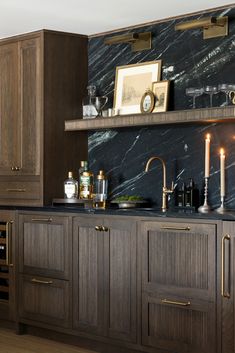 a kitchen with wooden cabinets and marble counter tops, candles on the shelf above the sink