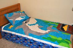 a child's bed with a shark quilt on it