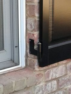 a black door is open on a brick building