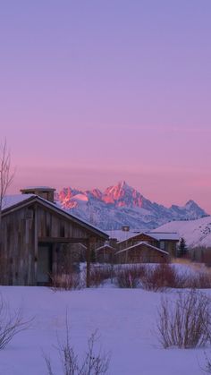 the mountains are covered in snow at sunset