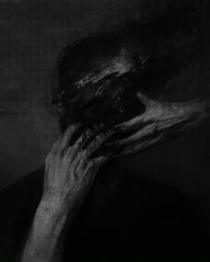 a black and white photo of a person covering their face with his hands in the dark