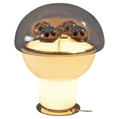 a table lamp that has three balls on the top and one is lit up with a white light