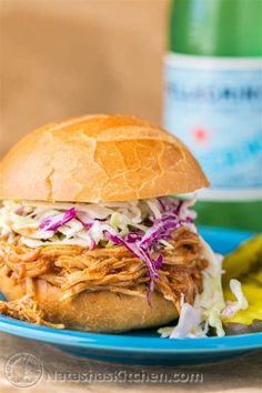 a pulled pork sandwich with coleslaw and pickles on a blue plate next to a banana