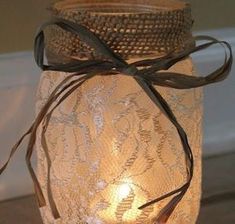 a mason jar filled with lace and a lit candle