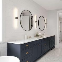 a large bathroom with two sinks and mirrors on the wall next to a bathtub