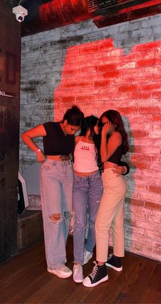 three girls standing in front of a brick wall