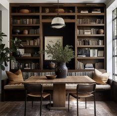 a dining room table and chairs with bookshelves in the background