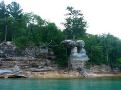 a rock formation in the middle of a body of water with trees on both sides