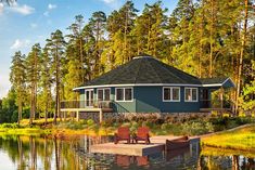 a house sitting on top of a lake next to a forest filled with lots of trees