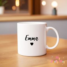 a white coffee mug with the word emma written in black on it sitting on a wooden table