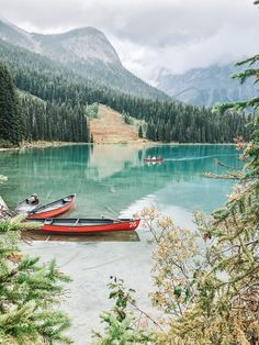 two canoes are docked on the shore of a mountain lake