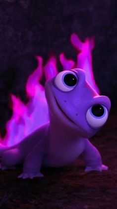 a purple toy with big eyes sitting in front of a rock wall and flames on the ground