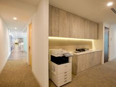 an empty office with a printer on the floor next to a cabinet and counter top