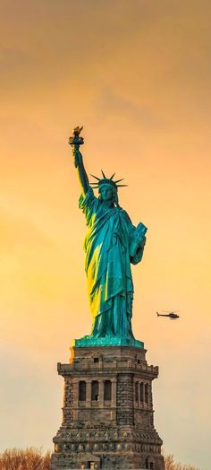 the statue of liberty is lit up at sunset