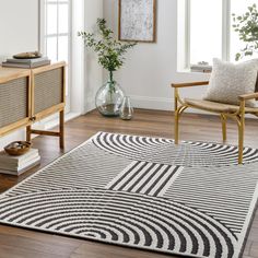 a living room with white walls and wooden floors, an area rug that has black and white designs on it