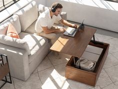 a man sitting on a couch using a laptop computer while wearing headphones and listening to music