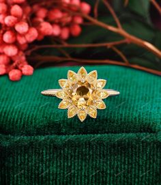 a yellow diamond ring sitting on top of a green cloth next to red and pink flowers