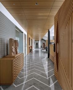 the hallway is lined with wooden sculptures and chevron patterns on the floor, along with white walls