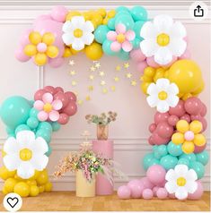 the balloon arch is decorated with pastel colors and white flowers for a baby's first birthday