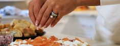 a close up of a person cutting food on a table with other foods in the background