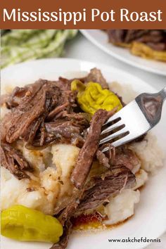 a white plate topped with meat and mashed potatoes covered in gravy next to a fork