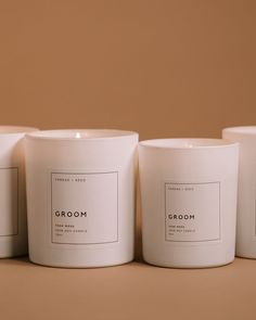 three white candles sitting next to each other on top of a brown surface with the words groom written in black