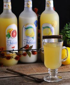 three bottles of lemonade next to a glass filled with liquid