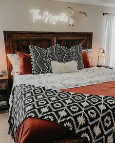 a bed with black and white bedspread next to a window in a bedroom