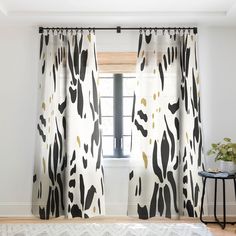 a living room with white walls, black and gold curtains and a rug on the floor