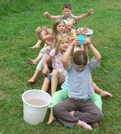 a group of children sitting on the ground with their hands in the air