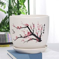 a coffee cup sitting on top of a table next to a book and potted plant