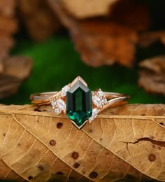 an emerald colored ring sitting on top of a leaf